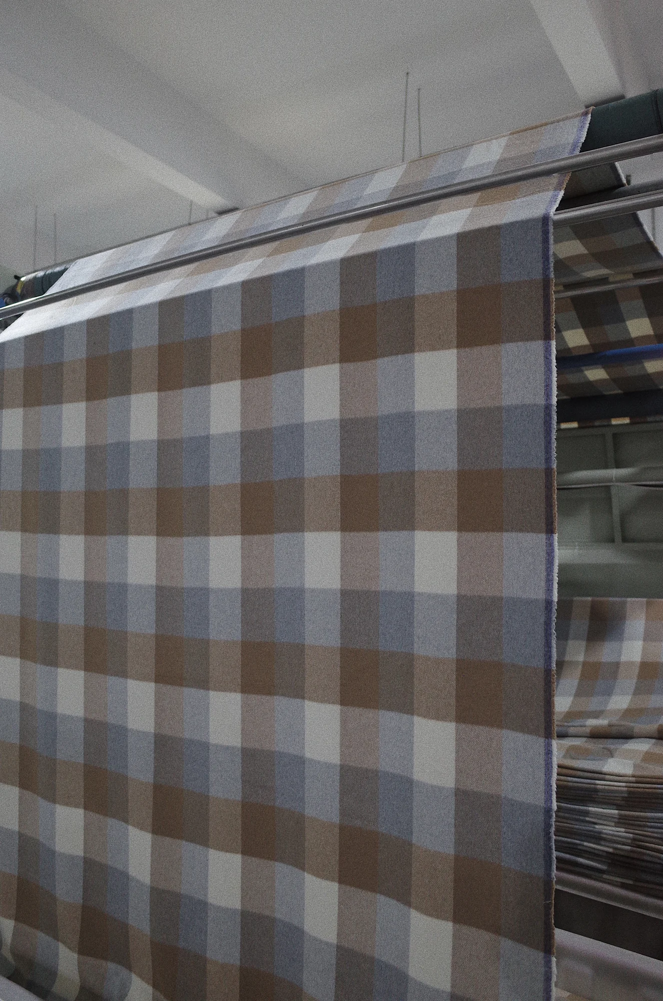 Checked finished fabric moving through finishing equipment at Fred Textile