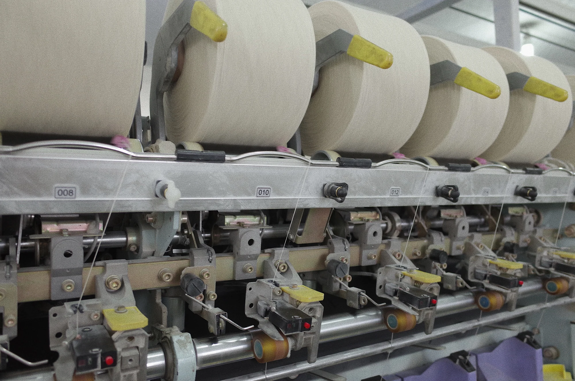 Close-up of spinning machine spools and mechanical controls at Fred Textile