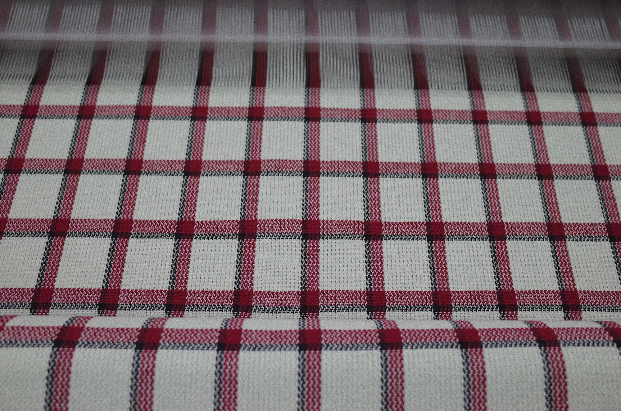 Red and black tartan pattern forming during weaving at Fred Textile