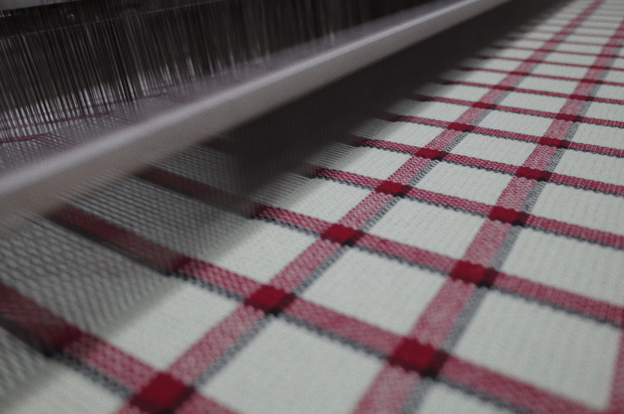 Close-up of a loom weaving red and black tartan fabric at Fred Textile