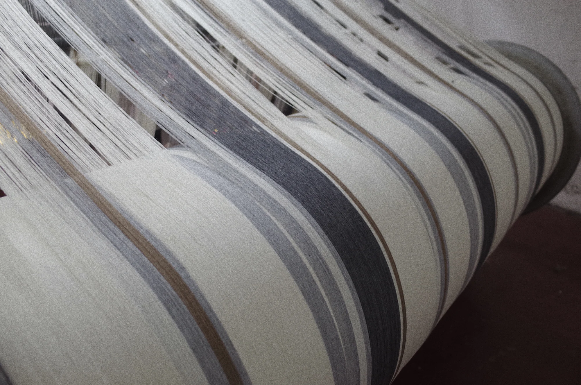 Light-coloured warp yarn and woven fabric roll at Fred Textile